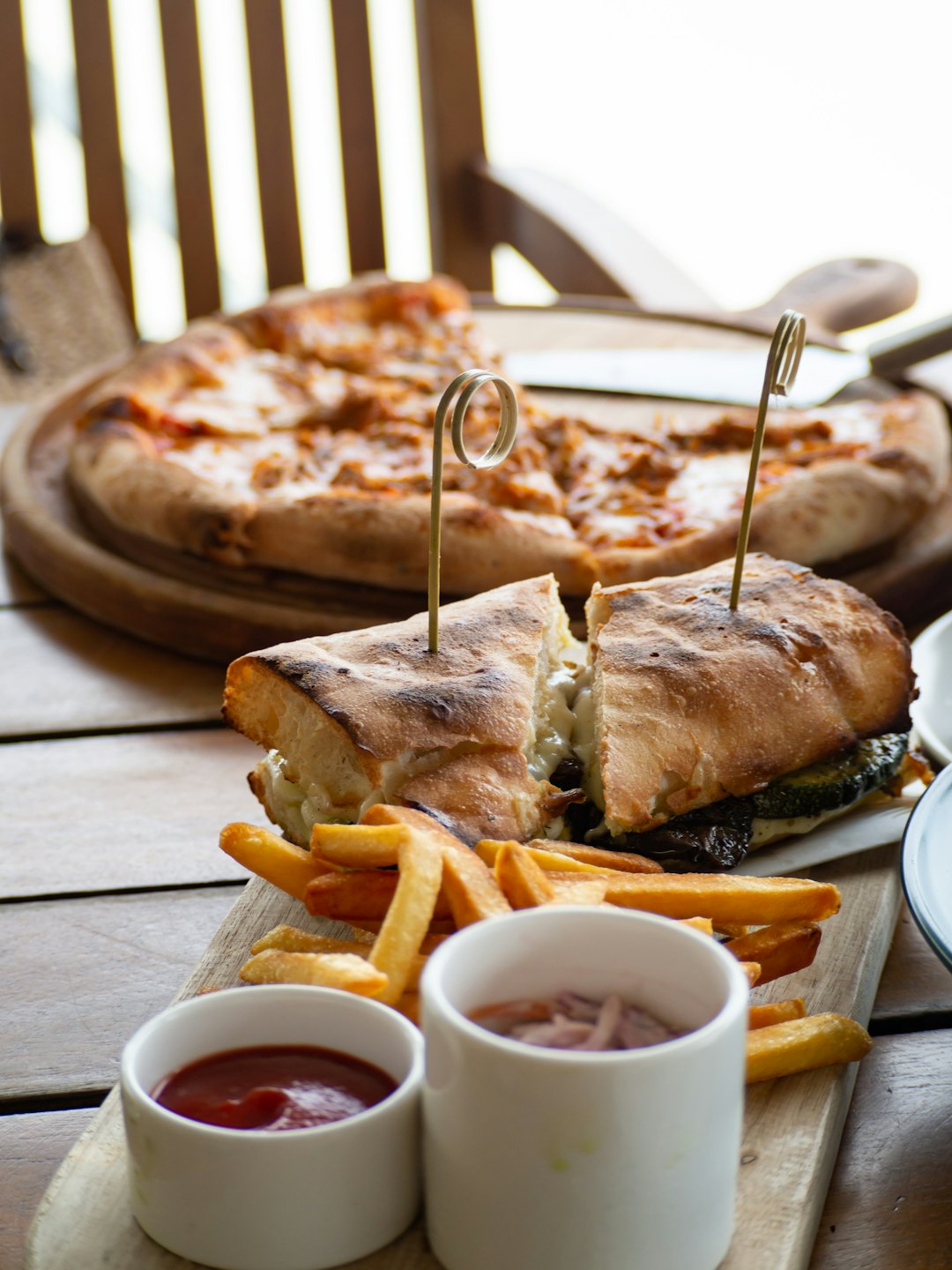 Gourmet broodje met friet en bijgerechten op een plank.