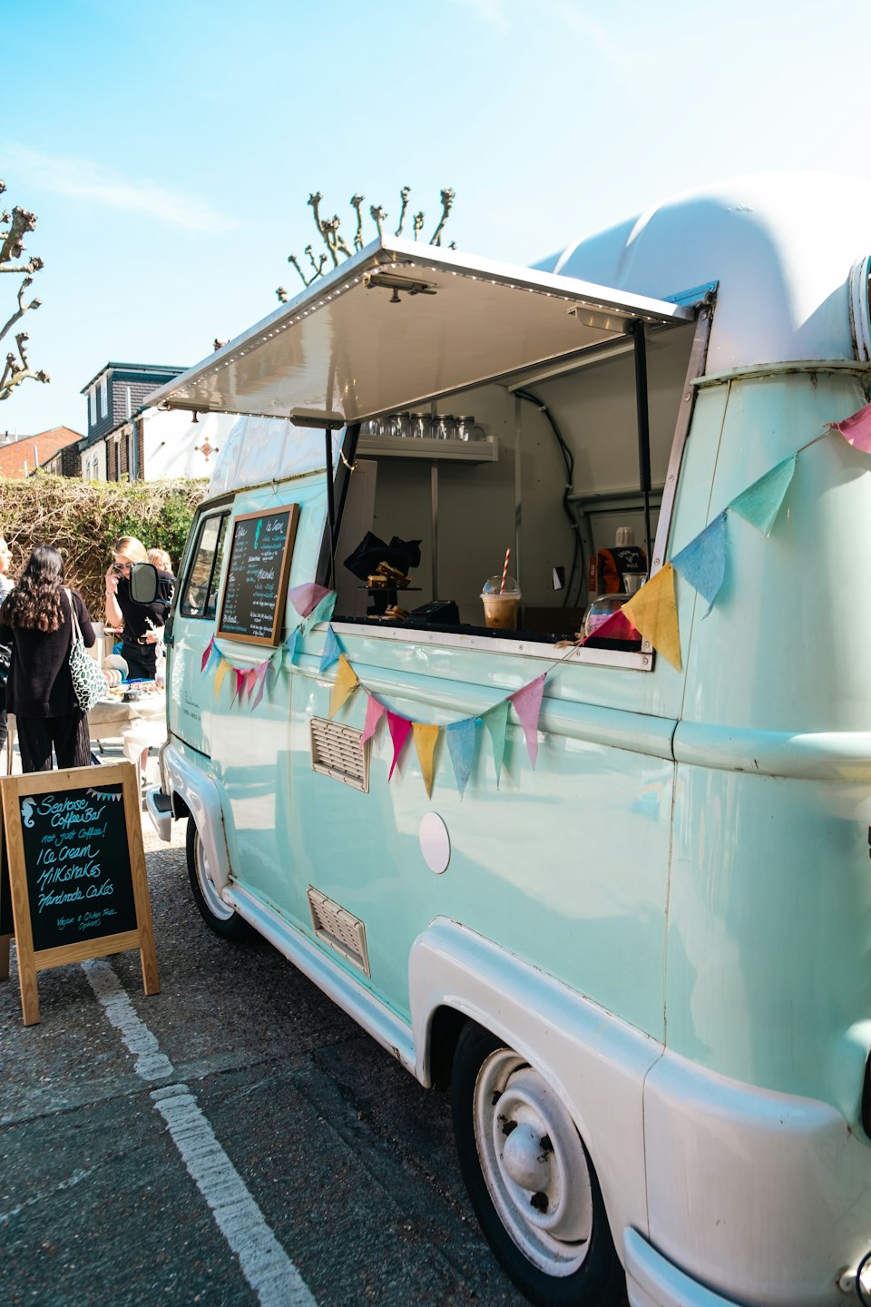 Mintgroene foodtruck met openstaande serveerluik op een zonnige dag.