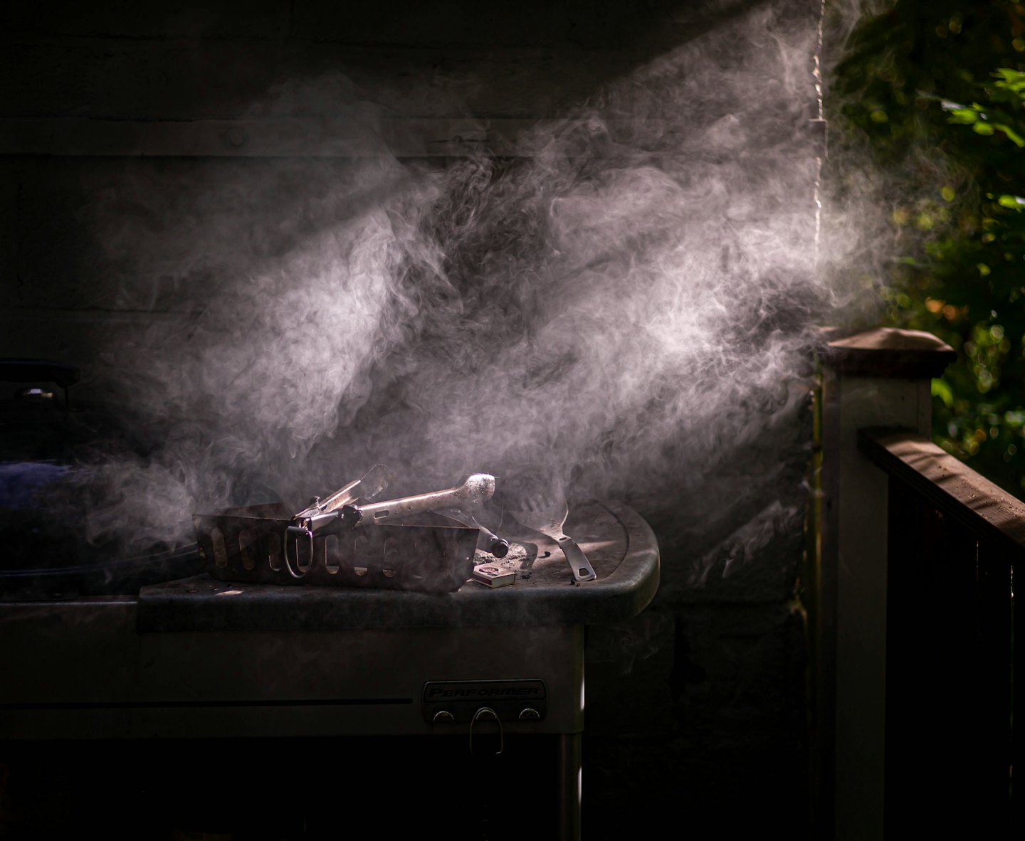 Rook stijgt op uit een houtskoolgrill op een terras.